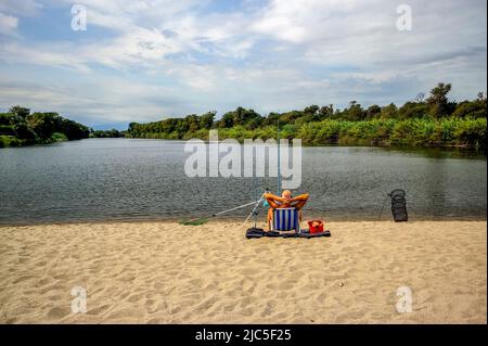 Canet-en-Roussillon, Francia, uomo in pensione pesca sulla spiaggia del fiume la Tut vicino a Perpignan, anziano solitudine, vecchiaia Foto Stock