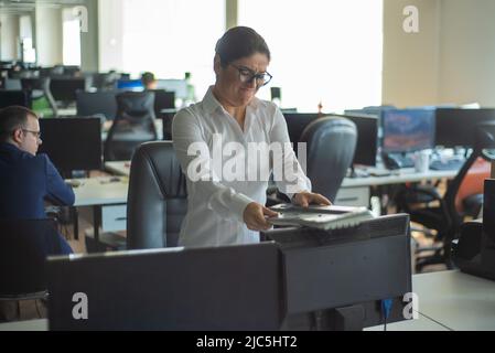 Una donna si libera e si deprime per un errore e rompe la tastiera sul monitor. Il manager femminile si arrabbia e si blocca un computer. Ufficio Foto Stock