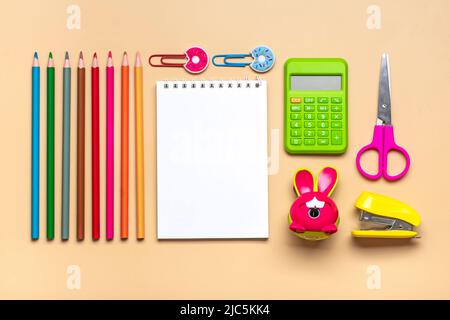 Telaio da forniture per scuole e uffici clip di carta, penne, calcolatrice, affilatrice, blocco note, Pinzatrice isolata su sfondo beige Flat lay Vista dall'alto Indietro t Foto Stock
