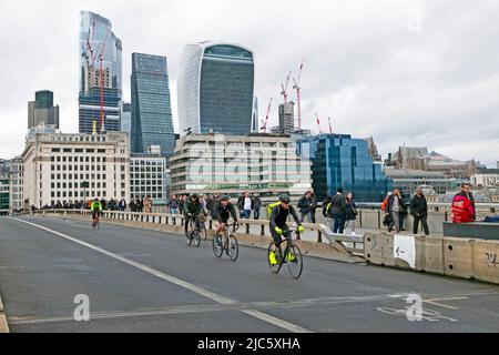 Ciclisti e lavoratori che attraversano London Bridge andando a casa dopo il lavoro e gli edifici, paesaggio urbano nel mese di aprile 2022 Londra Inghilterra Regno Unito KATHY DEWITT Foto Stock