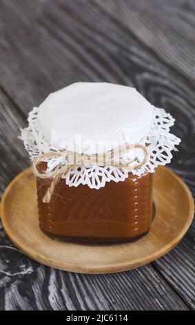 Caramello dolciario in vasetti di vetro. Decorato con carta artigianale e spago legato in un arco. Primo piano. Foto Stock