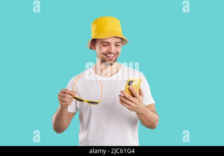 Allegro ragazzo gioioso con il telefono cellulare utilizza le applicazioni mobili e comunica sui social network. Foto Stock