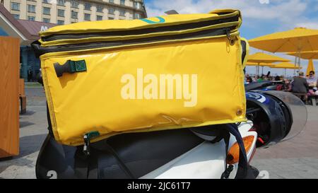 Consegna Courier scooter a motore con zaino giallo. Un corriere su uno scooter è in attesa di un ordine. Consegna rapida di merci ai clienti da tutto il resto Foto Stock