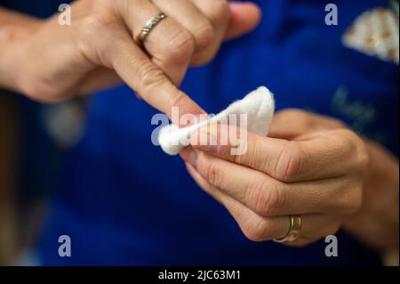 Closeup vista di una donna pulizia unghie lucidare via le sue unghie con un tampone di cotone. Foto Stock