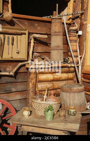 Sistemazione di vecchi oggetti popolari tradizionali all'esterno di un fienile in Romania. Briciolle di burro di legno. Foto Stock