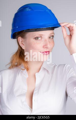 Giovane ingegnere donna che indossa un elmetto blu sta facendo alcuni gesti Foto Stock