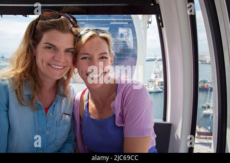 Due signore sorridenti sulla ruota del Capo, la ruota panoramica, il lungomare, città del Capo. Foto Stock