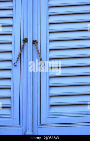 Chiusure per finestre vintage o gancio per serramenti in metallo o gancio per finestre montato su pareti in legno blu Foto Stock