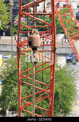 Ganci della gru mobile sul meccanismo di sollevamento con gancio di traino e cavo in acciaio della gru a ponte della macchina. Foto Stock