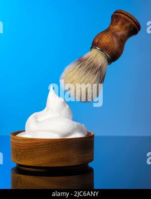 spazzola e schiuma da barba su sfondo blu. Foto Stock