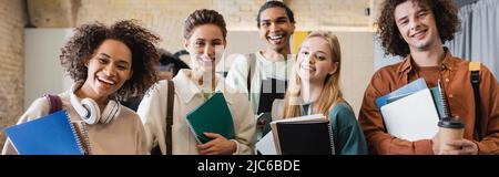 giovani e allegri studenti multietnici con copybooks sorridenti a macchina fotografica, banner Foto Stock