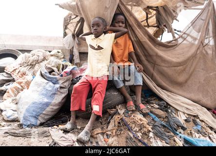 Due bambini africani disperati e giovani seduti su pneumatici e rifiuti su un enorme discarica di rifiuti in un villaggio vicino a Bamako, in Mali (Africa). Foto Stock