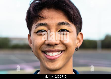 Felice uomo gay asiatico sorridendo davanti alla macchina fotografica Foto Stock