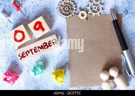 Settembre 9. Data del mese di settembre. Cubo di numeri con un fiore e un quaderno su tavolo in legno Diamond per lo sfondo. Foto Stock