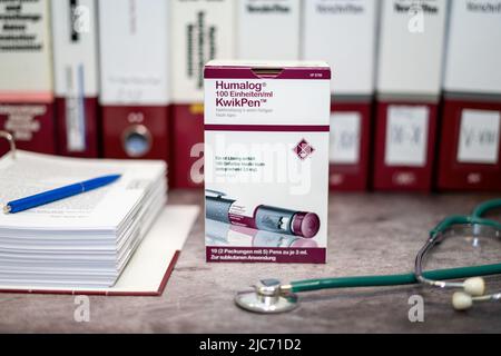 Humalog KwikPen contiene insulina lispro per il trattamento del diabete di tipo 1 e tipo 2, su un tavolo e in background diversi libri medici. Foto Stock