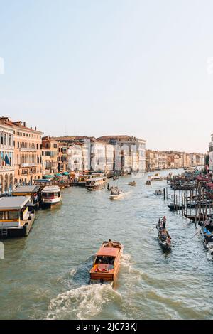 Venezia, Italia - 21 maggio 2022: Barche e gondole che attraversano il Canal Grande e gli edifici del Ponte di Rialto a Venezia, capitale del Veneto regi Foto Stock