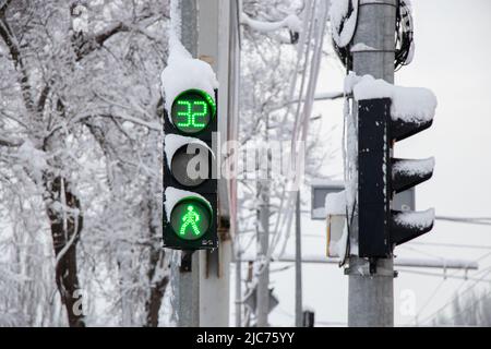 Un semaforo verde in inverno in neve e ghiaccio in Ucraina nella città di Dnipro, le strade sono state sollevate, un semaforo in città Foto Stock