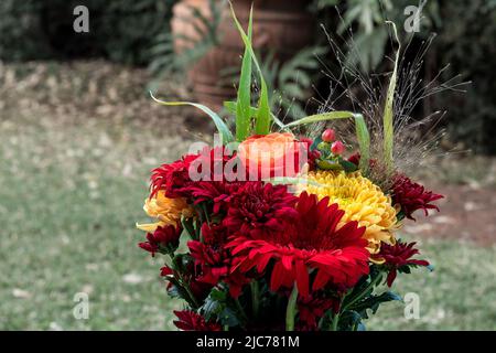 Un bouquet di fiori con rose rosse e margherite rosse Foto Stock