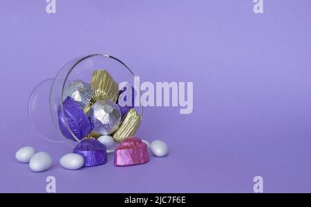 Concetto di festa, tradizionale turco Ramadan dolce zucchero caramella, e cioccolatini in una ciotola di vetro con sfondo viola. Foto Stock