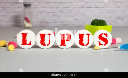 Close up of Lupus word on the table with drugs, stethoscope, syringe, and diabetes lancet glucometer Stock Photo