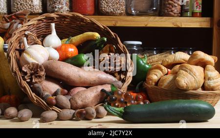 Cestini di verdure fresche e pane in cucina con vasetti di cibo essiccato in background Foto Stock