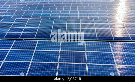 Volo aereo con vista dei droni sui pannelli solari in primo piano il giorno di sole. Pannello solare fotovoltaico. Spostamento su pannelli solari con bagliore solare. Produzione di energia alternativa rinnovabile. Energia ecologica verde Foto Stock