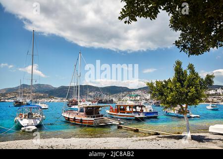 Vista di Bodrum Beach dalla Promenade. Barche a vela, barche a mare Egeo con tradizionali case bianche sulle colline a Bodrum porto città Turchia Foto Stock