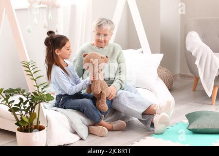 Bambina con giocattolo e nonna in camera da letto Foto Stock