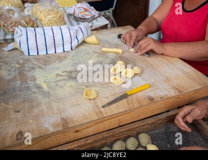 Bari, Puglia, Italia. Agosto 2021. Foto ravvicinata delle mani esperte di una donna anziana mentre prepara le orecchiette: Specialità di pasta locali. Con Quick ges Foto Stock