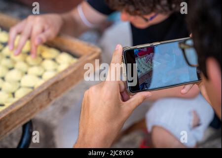 Bari, Puglia, Italia. Agosto 2021. Un giovane caucasico che osserva con curiosità e stupore la pasta tipica del luogo: Orecchiette. Un altro ragazzo Foto Stock