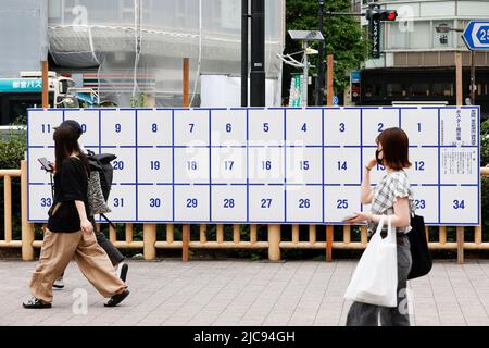 I pedoni camminano accanto a un cartello elettorale eretto per le prossime elezioni della Casa superiore fuori dalla Stazione di Takadanobaba il 11 giugno 2022, Tokyo, Giappone. L'elezione della Camera dei Consiglieri si terrà il 10 luglio. Credit: Rodrigo Reyes Marin/AFLO/Alamy Live News Foto Stock