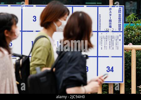 I pedoni camminano accanto a un cartello elettorale eretto per le prossime elezioni della Casa superiore fuori dalla Stazione di Takadanobaba il 11 giugno 2022, Tokyo, Giappone. L'elezione della Camera dei Consiglieri si terrà il 10 luglio. Credit: Rodrigo Reyes Marin/AFLO/Alamy Live News Foto Stock