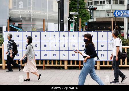 I pedoni camminano accanto a un cartello elettorale eretto per le prossime elezioni della Casa superiore fuori dalla Stazione di Takadanobaba il 11 giugno 2022, Tokyo, Giappone. L'elezione della Camera dei Consiglieri si terrà il 10 luglio. Credit: Rodrigo Reyes Marin/AFLO/Alamy Live News Foto Stock