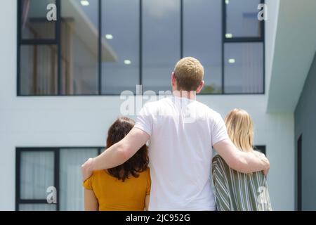 Ritratto di famiglia caucasico che guarda ad una nuova casa in movimento nel giorno. Foto Stock