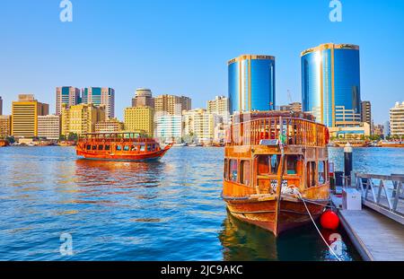 DUBAI, Emirati Arabi Uniti - 1 MARZO 2020: La barca dhow è ormeggiata al molo sul Dubai Creek con una vista sulla banca Deira con alloggi moderni e le Torri gemelle Deira (Ro Foto Stock