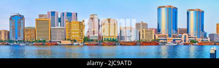 DUBAI, Emirati Arabi Uniti - 1 MARZO 2020: Panorama del Dubai Creek, linea di barche in sambuco in legno sulla riva del quartiere Deira e i suoi edifici moderni in backgroun Foto Stock