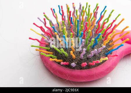 Pettine multicolore con capelli caduti. Cura dei capelli. Problemi, perdita di capelli. Trichologo, procedure per la cura dei capelli. Capelli aggrovigliati su un pettine. Un pettine per bambini, un pettine Foto Stock