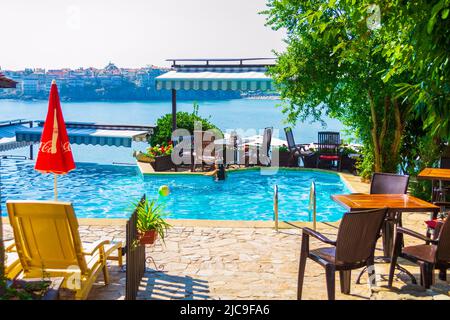 Patio con piscina blu e posti a sedere all'aperto con vista sulla splendida baia di Sozopol, Bulgaria Foto Stock