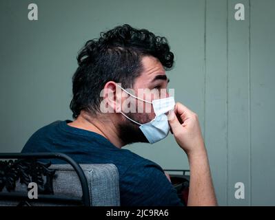 Medellin, Antioquia, Colombia - Febbraio 19 2022: L'uomo bianco indossa la maschera e gli graffia il naso Foto Stock