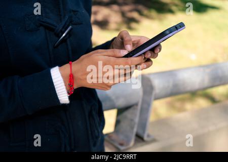 Le mani di una giovane donna digitano un messaggio di testo su uno smartphone o un cellulare. Concetto di comunicazione. Foto Stock