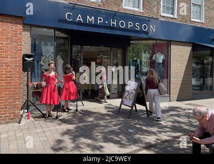 Newbury, Berkshire, Inghilterra, Regno Unito. 2022. Cantanti in abiti rossi seranade passa vicino sulla High Street a Newbury in un pomeriggio di sole. Inghilterra Regno Unito. Foto Stock