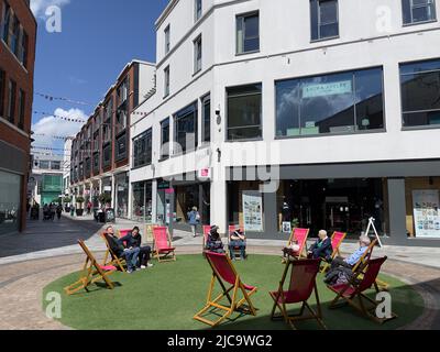 Newbury, Berkshire, Inghilterra, Regno Unito. 2022. Sedie a sdraio in erba per gli amanti dello shopping nel centro città. Foto Stock