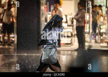 Una donna ripara dalla pioggia sotto un cappotto. Ad Ankara, la capitale della Turchia, cadono forti piogge. Foto Stock