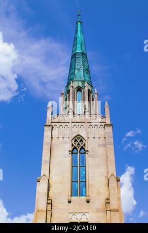 Guglia di rame sulla torre della chiesa contro il cielo con le nuvole violacche Foto Stock