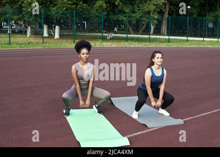 I giovani amici si accaparrano allo stadio, si riscaldano prima di fare esercizi di gruppo Foto Stock