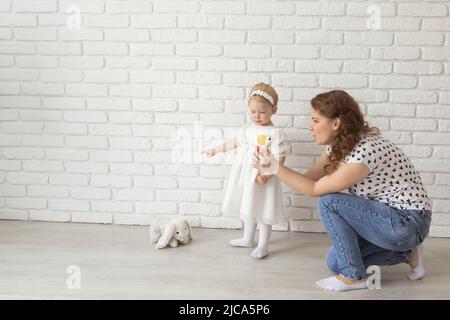 Banner bambino con apparecchi acustici e impianti cocleari gioca con i genitori sul pavimento, copia passo. Concetto di sordi e riabilitazione e diversità Foto Stock