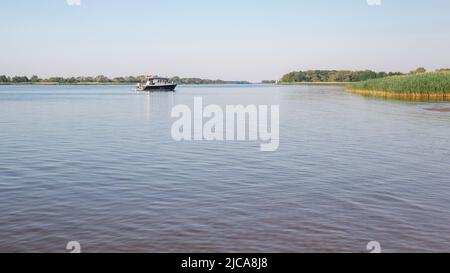 In una giornata estiva limpida, una piccola barca da pesca torna a casa Foto Stock