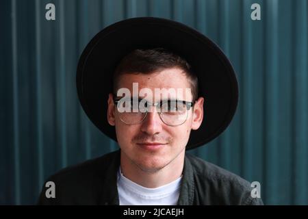 Felice uomo intelligente sorridente. Ritratto di bello sorridente elegante Hipster modello Lamberseual. Uomo vestito di occhiali e cappello nero. Maschio sul moderno Foto Stock