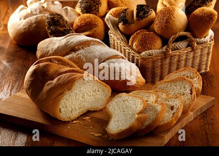 vari tipi di pane serviti su un tavolo di legno e cestino di rattan Foto Stock