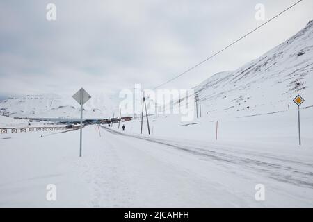 Una strada coperta di neve che conduce torreggiare una città in lontananza Foto Stock